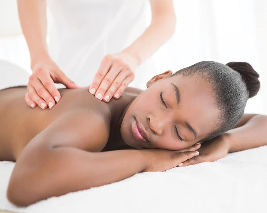 woman laying on her stomach receiving therapeutic back massage